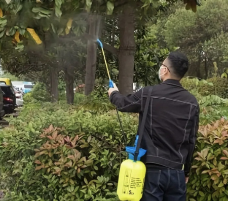 5L Pressure Sprayer in use - person spraying trees and garden shrubs with shoulder strap
